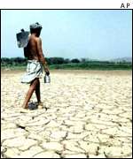 Man walks across drought-scarred lakebed AP